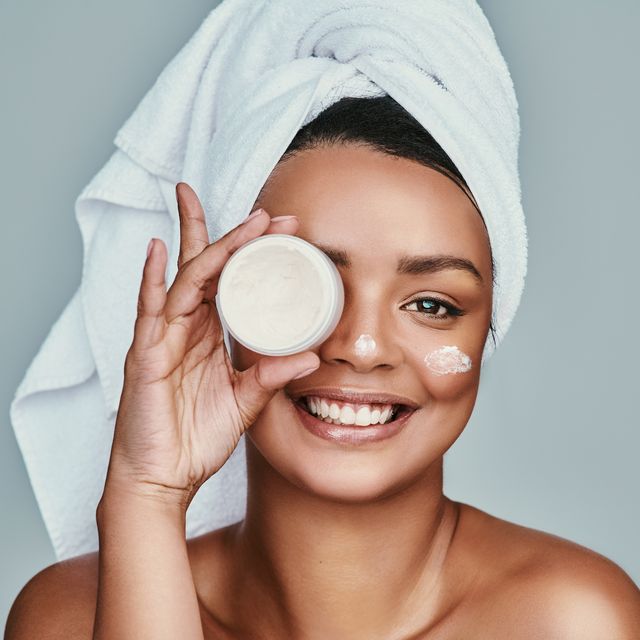 cropped shot of a beautiful young woman posing with a pot of moisturizer