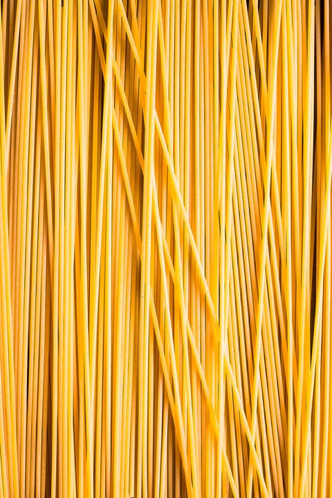heap of uncooked whole wheat spaghetti italian pasta, top view pasta pattern food background