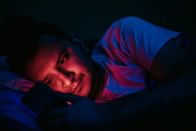 man lying in bed and using smartphone spending time during pandemic lockdown coronaviruscovid 19