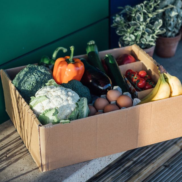 a delivery box filled with fresh organic vegetables and fruits on the front yard