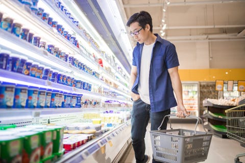 un homme chinois d'âge mûr tient un panier et parcourt les produits dans la section des produits surgelés