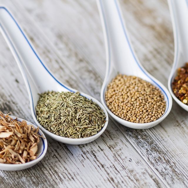 spices and herbs in porcelain spoons over a wooden background