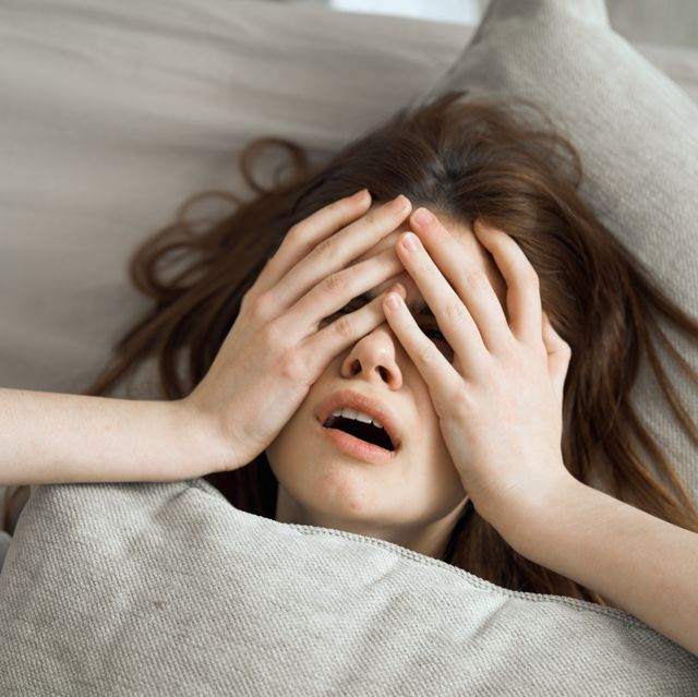 the woman lies in bed and woke up with a terrible headache and poor health