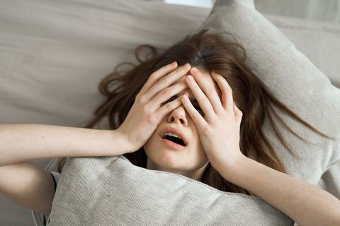 the woman lies in bed and woke up with a terrible headache and poor health