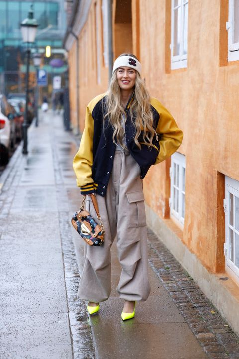 copenhagen, denmark   february 01 emili sindlev wearing a headband by chanel, a dark blue and yellow college jacket, beige pants, yellow pumps and a multicolored bag by louis vuitton, seen at the kernemilk fashion show during copenhagen fashion week autumnwinter 2022 on february 1, 2022 in copenhagen, denmark photo by streetstyleshootersgetty images