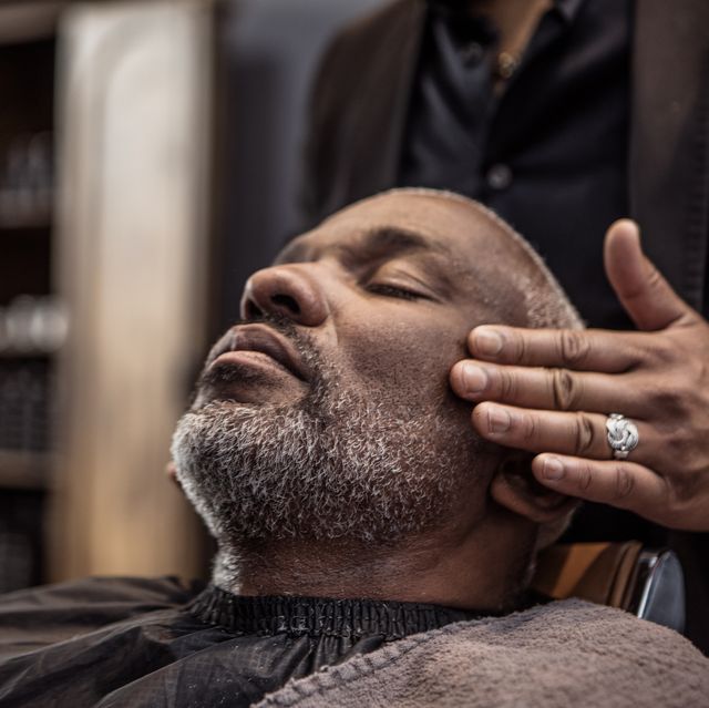 handsome middle aged black man enjoying a beard trim in a luxury european barber shop