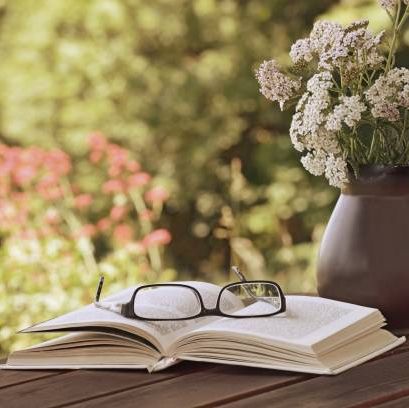 vase with wild flowers achillea, book and glasses on the table