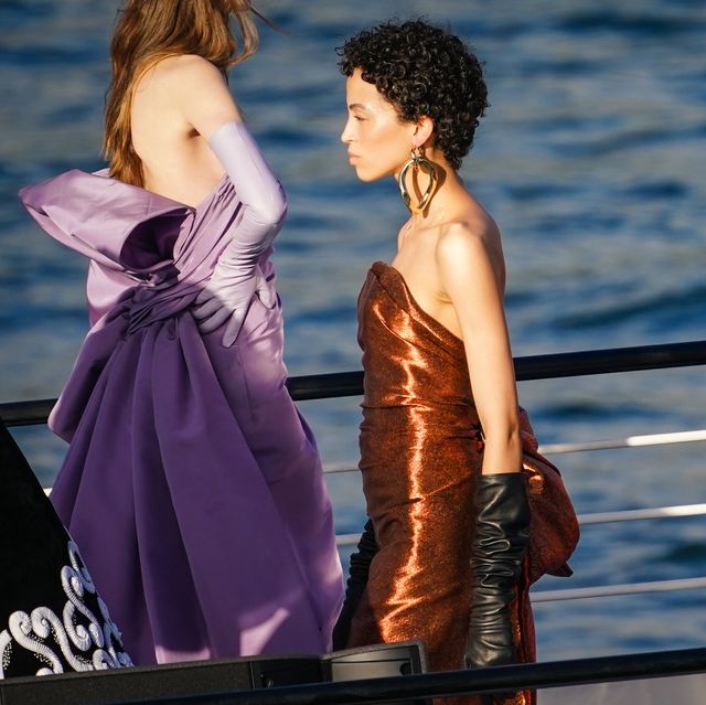 paris, france   july 05 a model wears a large golden earring, a bronze color shiny lustrous silky off shoulder dress, black leather gloves, during the balmain sur seine performance, on a barge on the seine river, on july 05, 2020 in paris, france photo by edward berthelotgetty images