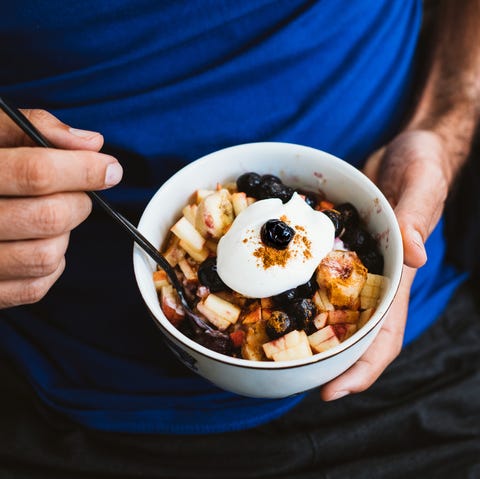 A man eating porridge blueberry, banana, almond, cinnamon, vegan yogurt, oats, apple