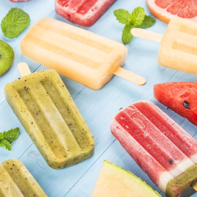 healthy whole fruit popsicles with berries kiwi watermelon cantaloupe on wooden vintage table