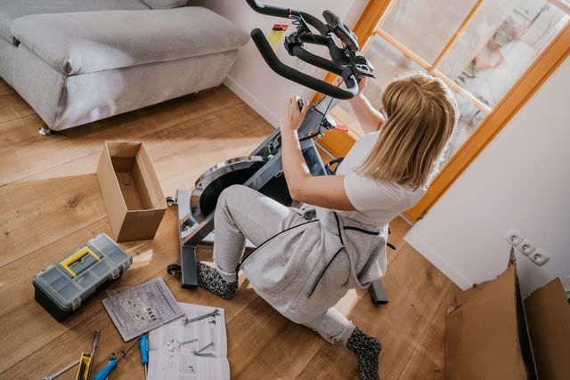 a person sitting on the floor putting an exercise bike together