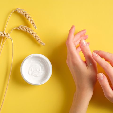 female hands applying wheat, barley and oat hand cream on yellow background natural skin care cosmetics, organic beauty product concept