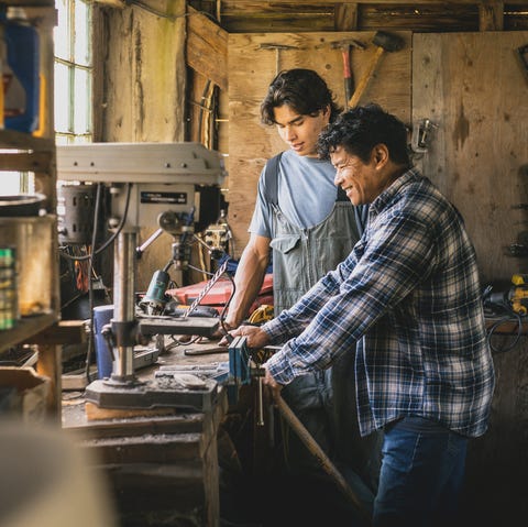 Father teaching son in workshop father teaching adult son in farm workshop