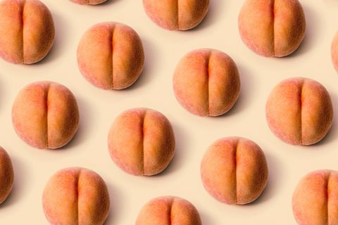 a detailed image of a freshly picked ripe peach  photographed on a peach colored background