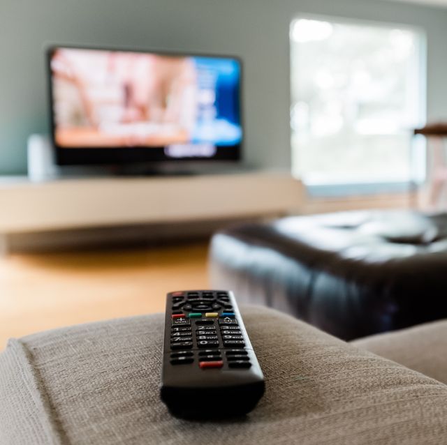 close up of a remote control sitting on a couch in an empty modern living room