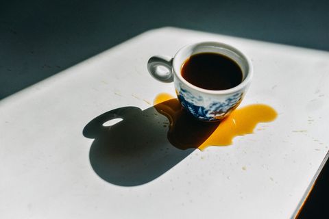 espresso cup filled with spilled coffee around