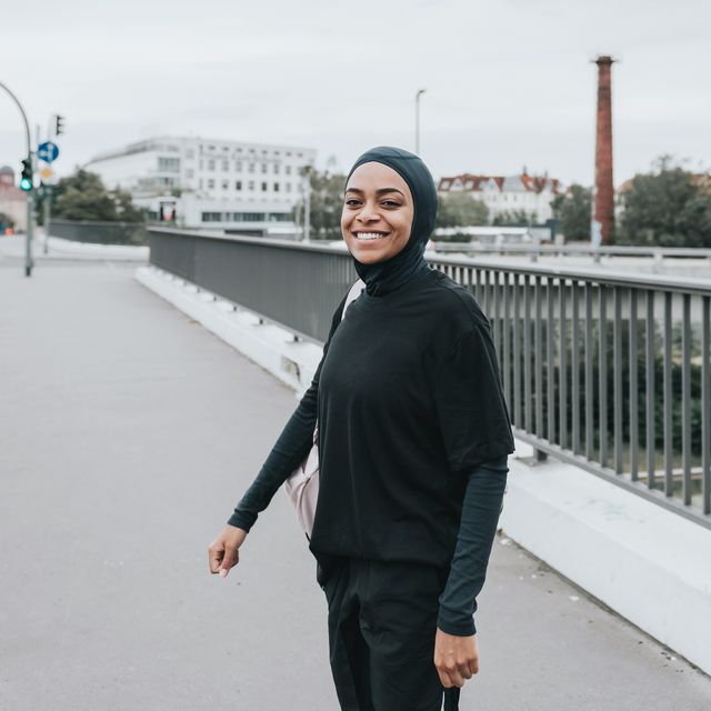 young smiling muslim sports woman with sports hijab standing on crossroad in berlin