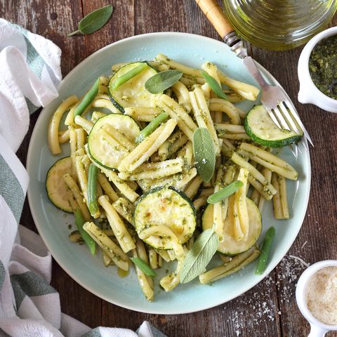 italian penne pasta with roasted zucchini, pesto sauce and green beans, olive oil and sage dressing top view