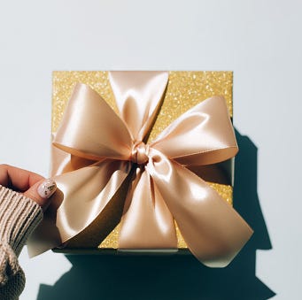 top view of anonymous woman with manicure touching striped present during holiday celebration against gray background holiday concept