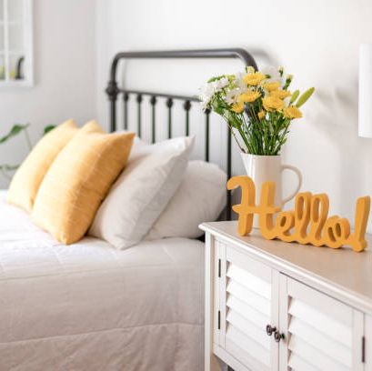 cheerful yellow hello sign and fresh flowers in a clean and bright bedroom