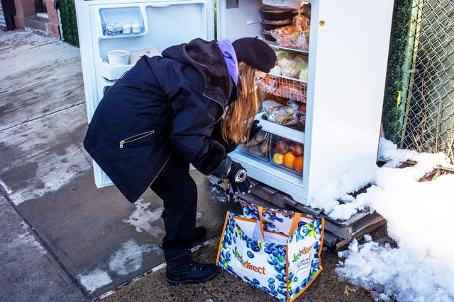 woman in snow in front of community fridge