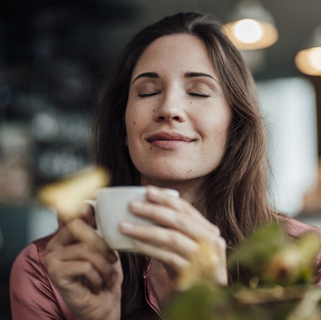 smiling businesswoman smelling coffee in cafe