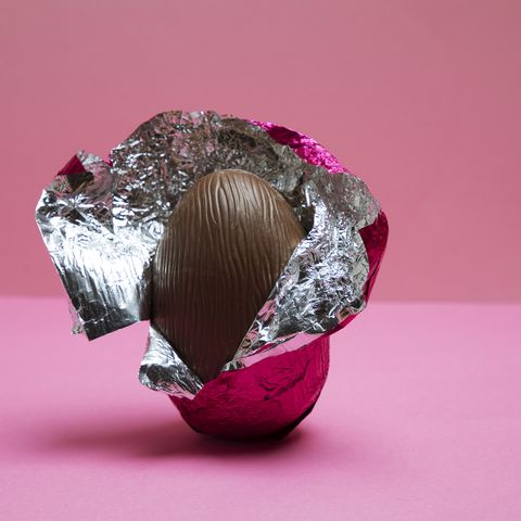 a half unwrapped easter egg on a pink background