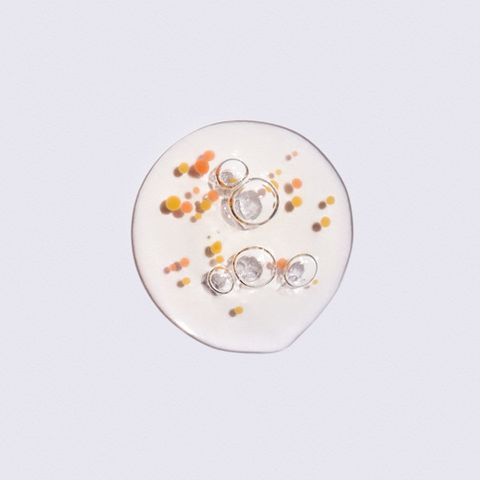 drop of organic essential oil or natural moisturizing lotion with air bubbles and orange particles on white background flat lay style beauty and health care concept