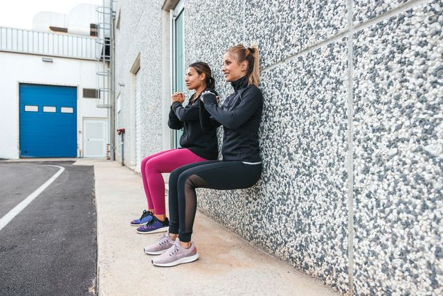 two women exercising outdoor doing wallsit