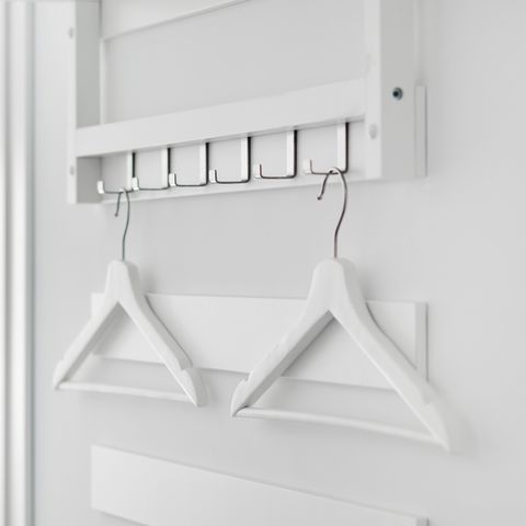 two white wooden hangers hanging on a hook on a white wall in hallway, no people, closeup