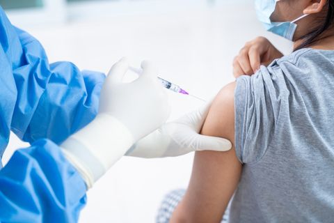 doctor making a vaccination in the shoulder of patient teens girls person, flu vaccination injection on arm, coronavirus,covid 19 vaccine disease preparing for human clinical trials vaccination shot