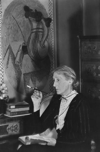 retrato de la escritora británica virginia woolf 1882 1941 mientras fuma un cigarrillo con un libro abierto en su regazo, londres, inglaterra, 1939 en la pared detrás de ella hay un fresco pintado por su hermana, vanessa bell foto de gisele freund