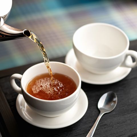 aromatic hot black tea pouring into white cups from metal kettle good morning concept soft focus