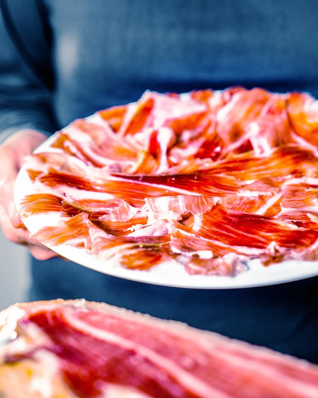 anonymous person holding a plate of delicious iberian ham sommelier cutting a leg of 100 iberian ham appetizing slices of iberian ham acorn fed iberian ham typical spanish or catalan food