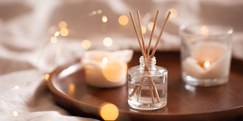 home perfume in glass bottle with wood sticks, scented burn candles  tray in bedroom close up aromatherapy cozy atmosphere lifestyle winter warm xmas season