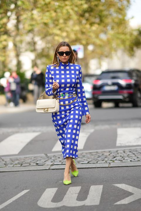 paris, france   october 02 julia comil wears silver rhinestones pendant earrings, black sunglasses, a blue and white checkered print patter turtleneck  long sleeves  belted  midi tube dress, a gold chains and green stones pendant belt, a white leather with braided borders handbag from fendi, neon green shiny leather pointed  cut out pumps heels shoes, outside vivienne westwood, during paris fashion week   womenswear spring summer 2022, on october 02, 2021 in paris, france photo by edward berthelotgetty images