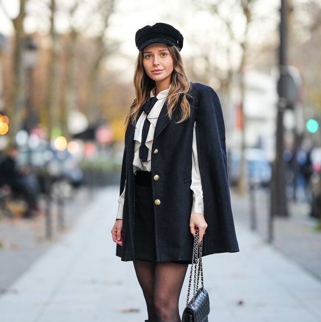 paris, france   november 24 diane batoukina wears a black velvet cap from zara, a white latte ruffled shirt, a black silk knot tie, a black oversized  shoulder pads  cloak, black tights, high waist black shorts, a black shiny grained leather timeless handbag from chanel, black shiny leather pointed knees boots  high boots, during a street style fashion photo session, on november 24, 2021 in paris, france photo by edward berthelotgetty images