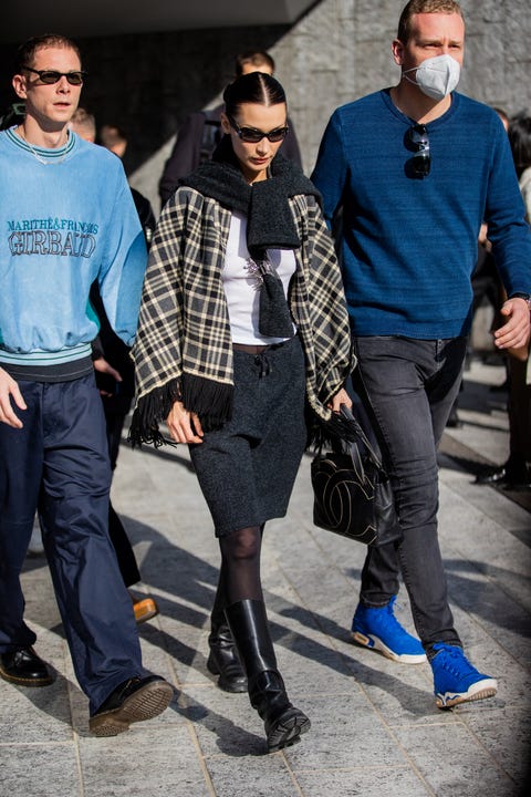 milan, italy   february 24 model bella hadid is seen wearing chanel bag, checkered scarf, grey skirt, sheer tights, knee high boots in black with boyfriend marc kalman wearing blue jumper, navy pants outside max mara fashion show during the milan fashion week fallwinter 20222023 on february 24, 2022 in milan, italy photo by christian vieriggetty images
