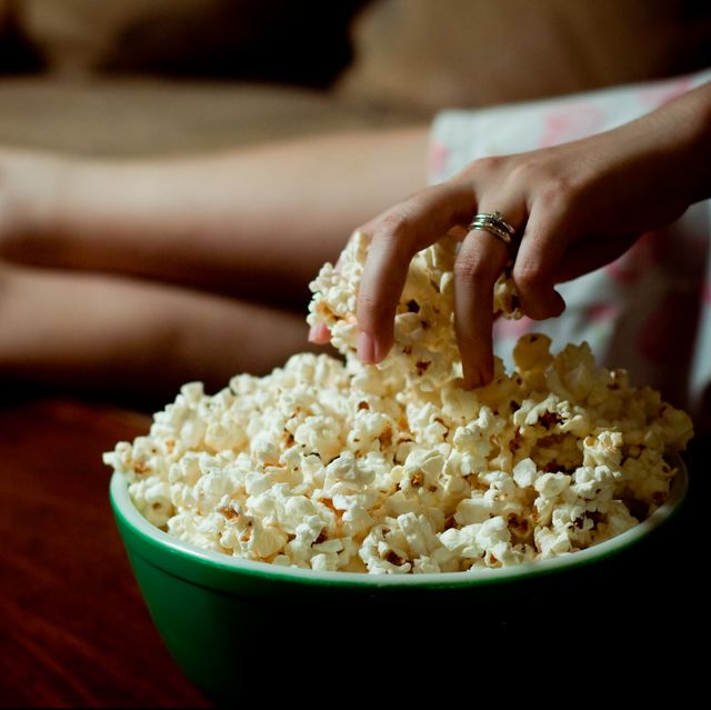 Woman hand into bowl of popcorn