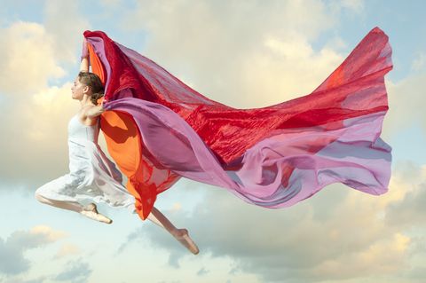 Caucasian woman floating through air with scarves