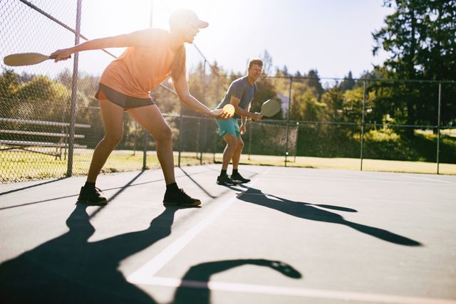 a youthful and fun caucasian couple in their 50s enjoy the recreational sport of pickleball on a warm day in the pacific northwest shot in washington state
