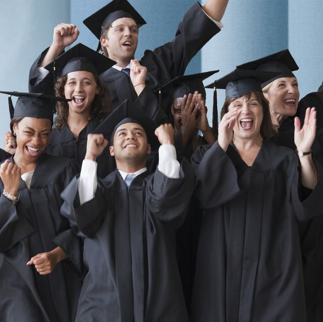 several graduates wearing black caps and gowns cheer and clap in front of a blue and grey background