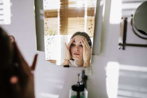 woman looking in bathroom mirror after cleaning her face