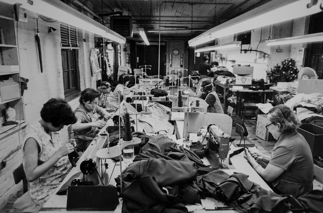 view of garment workers at sewing machines in a textile facility, new york, new york, 1975 photo by brownie harriscorbis via getty images