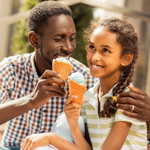 girl and father enjoying ice cream and smiling