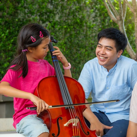 girl playing cello with her family at outdoor park girl playing cello with her family at outdoor park