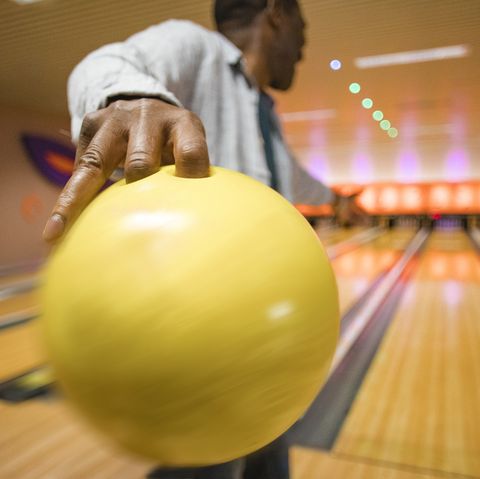 rear, close up shot of a senior man about to throw a bowling ball down the bowling alley