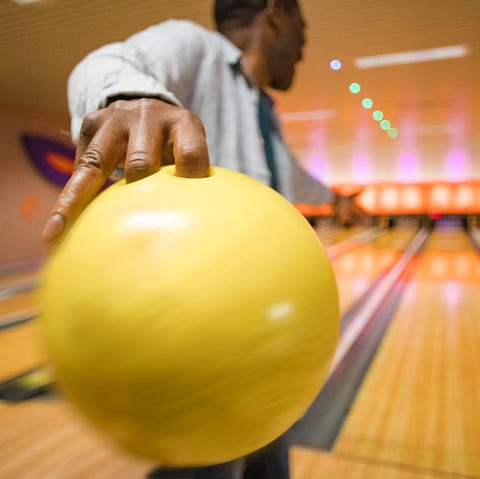 rear, close up shot of a senior man about to throw a bowling ball down the bowling alley rear, close up shot of a senior man about to throw a bowling ball down the bowling alley