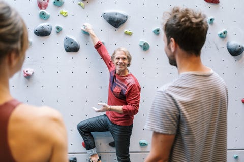 Smiling mature instructor teaching male and female students about bouldering in gym smiling mature instructor teaching male and female students about bouldering in gym