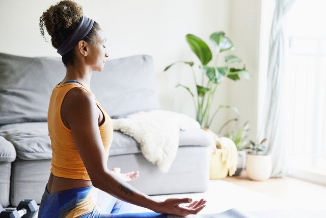 woman in lotus position while working out in living room of home